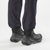 Rückansicht von Füßen in schwarzen Salomon-Wanderschuhen und dunklen Hosen.