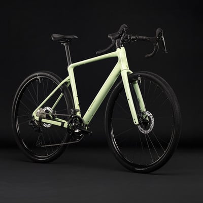 Hellgrünes Gravelbike mit schwarzen Rädern und dunklem Hintergrund. Hellgrünes Gravelbike mit schwarzen Rädern und dunklem Hintergrund.