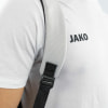 Detail eines Rucksack-Schultergurts auf einem weißen T-Shirt mit JAKO-Logo.