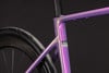Lila Fahrradrahmen mit UCI-Logo und schwarzem Reifen.