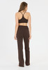 Eine Frau in braunem Sport-BH und High-Waist-Hose steht von hinten.