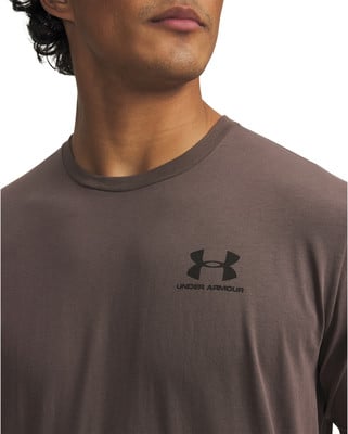 Detail von Hals und Brust eines Mannes in einem braunen T-Shirt mit Under Armour-Logo. Detail von Hals und Brust eines Mannes in einem braunen T-Shirt mit Under Armour-Logo.