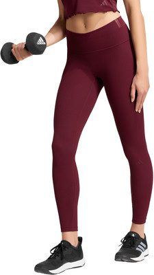 Eine Frau hält eine Hantel und trägt eine weinrote Leggings und schwarze Schuhe. Eine Frau hält eine Hantel und trägt eine weinrote Leggings und schwarze Schuhe.