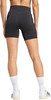 Eine Frau in schwarzen Shorts und weißen Socken mit Turnschuhen auf weißem Hintergrund.