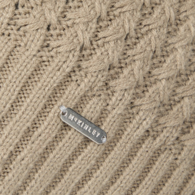 Detail eines Strickmusters mit McKinley-Logo auf beigem Hintergrund. Detail eines Strickmusters mit McKinley-Logo auf beigem Hintergrund.
