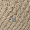 Detail eines Strickmusters mit McKinley-Logo auf beigem Hintergrund.