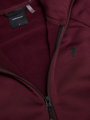 Detail des Innenraums eines weinroten Sweatshirts mit Peak Performance Logo und Reißverschluss.