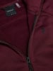 Detail des Innenraums eines weinroten Sweatshirts mit Peak Performance Logo und Reißverschluss.