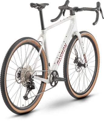 Grauer Gravelbike-Rahmen mit rotem RAYMON-Schriftzug und schwarzen Rädern. Grauer Gravelbike-Rahmen mit rotem RAYMON-Schriftzug und schwarzen Rädern.