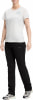 Frau in weißem T-Shirt und schwarzer Hose mit Logo auf dem Oberschenkel.