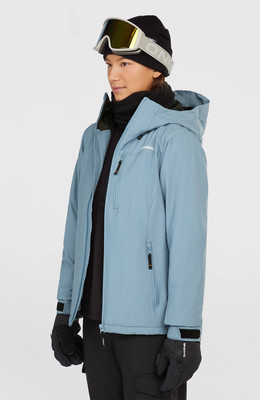 Eine Frau in einer blauen Skijacke, schwarzer Mütze und Brille.