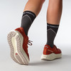 Damen-Laufschuhe von Salomon in Orange mit grauen Socken.