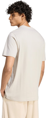 Ein Mann in einem beigen T-Shirt und Jogginghose mit lockigem Haar. Ein Mann in einem beigen T-Shirt und Jogginghose mit lockigem Haar.