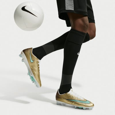 Ein Fußballspieler in goldenen Stollen und schwarzen Socken mit einem Ball. Ein Fußballspieler in goldenen Stollen und schwarzen Socken mit einem Ball.
