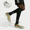 Ein Fußballspieler in goldenen Stollen und schwarzen Socken mit einem Ball.