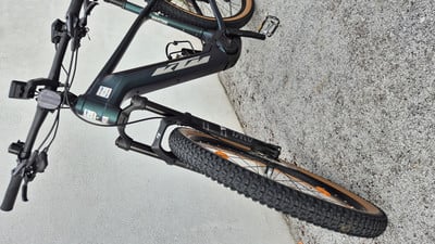 Ein dunkelgrünes E-Mountainbike steht auf Pflastersteinen. Ein dunkelgrünes E-Mountainbike steht auf Pflastersteinen.
