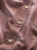 Stoffdetail mit Karomuster und Holzknöpfen.