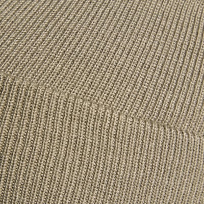 Detail eines Strickmaterials aus Wolle in Beige mit sichtbarer Rippenstruktur. Detail eines Strickmaterials aus Wolle in Beige mit sichtbarer Rippenstruktur.