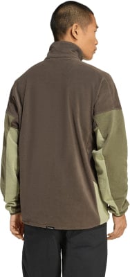Mann von hinten in braunem Fleece-Pullover mit grünen Ärmeln.