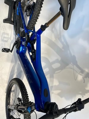 Ein blaues Mountain-E-Bike hängt an der Wand, mit sichtbarer Federung und Pedal. Ein blaues Mountain-E-Bike hängt an der Wand, mit sichtbarer Federung und Pedal.