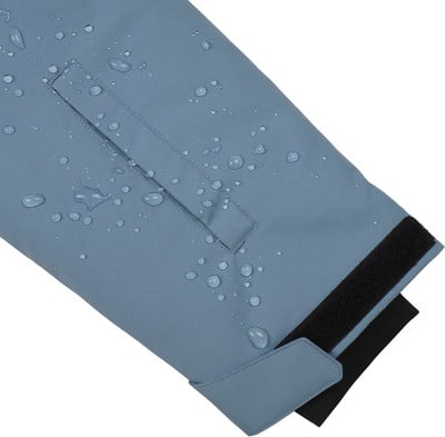Blaue Jacke mit Wassertropfen und Klettverschluss am Ärmel.