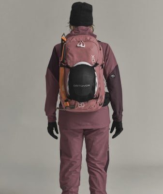 Eine Frau in Skibekleidung mit Rucksack und Eispickel auf dem Rücken.