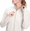 Eine Frau schließt eine cremefarbene Fleecejacke mit Reißverschluss am Hals.