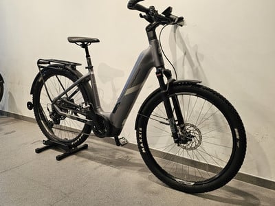 Ein graues E-Bike mit Federung und Gepäckträger steht auf einem Ständer. Ein graues E-Bike mit Federung und Gepäckträger steht auf einem Ständer.