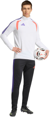 Ein Fußballer in einem weißen Oberteil mit lila Streifen und schwarzer Hose hält einen Ball. Ein Fußballer in einem weißen Oberteil mit lila Streifen und schwarzer Hose hält einen Ball.