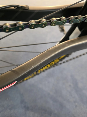 Detailaufnahme einer Fahrradkette mit bunten Gliedern und dem Fahrradrahmen.
