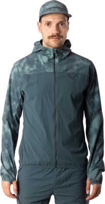 Mann in dunkelgrüner Kapuzenjacke und Mütze mit Dynafit-Logo. Mann in dunkelgrüner Kapuzenjacke und Mütze mit Dynafit-Logo.