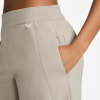 Detail einer Damen-Hose in Beige mit Tasche und Logo.