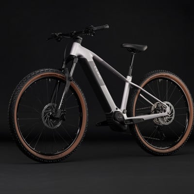 Silbernes Cube E-Bike mit braunen Reifen und schwarzem Hintergrund. Silbernes Cube E-Bike mit braunen Reifen und schwarzem Hintergrund.