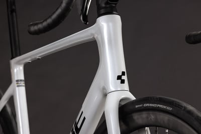 Detail eines weißen Fahrradrahmens mit schwarzem Logo und glänzender Oberfläche. Detail eines weißen Fahrradrahmens mit schwarzem Logo und glänzender Oberfläche.