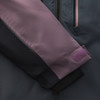 Ärmeldetail einer Jacke mit lila Klettverschluss und schwarzem Bündchen.