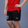 Ein Mann trägt ein rotes T-Shirt und eine schwarze Shorts mit PUMA-Logo und österreichischem Wappen.