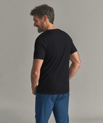 Ein Mann in einem schwarzen T-Shirt und blauer Hose lächelt. Ein Mann in einem schwarzen T-Shirt und blauer Hose lächelt.