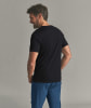 Ein Mann in einem schwarzen T-Shirt und blauer Hose lächelt.