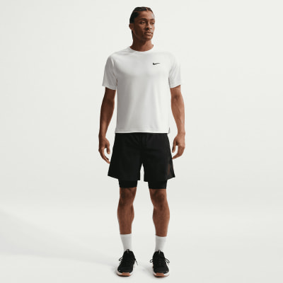 Ein Mann in einem weißen Nike-T-Shirt und schwarzen Shorts steht vor einem weißen Hintergrund. Ein Mann in einem weißen Nike-T-Shirt und schwarzen Shorts steht vor einem weißen Hintergrund.