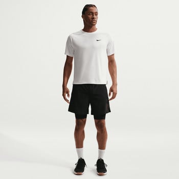 Ein Mann in einem weißen Nike-T-Shirt und schwarzen Shorts steht vor einem weißen Hintergrund.
