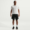Ein Mann in einem weißen Nike-T-Shirt und schwarzen Shorts steht vor einem weißen Hintergrund.