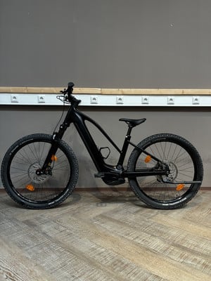 Ein schwarzes E-Bike steht auf einem Holzboden vor einer grauen Wand. Ein schwarzes E-Bike steht auf einem Holzboden vor einer grauen Wand.