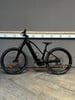 Ein schwarzes E-Bike steht auf einem Holzboden vor einer grauen Wand.