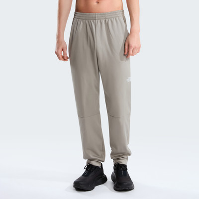 Ein Mann in grauen The North Face Jogginghosen und schwarzen Schuhen posiert vor weißem Hintergrund. Ein Mann in grauen The North Face Jogginghosen und schwarzen Schuhen posiert vor weißem Hintergrund.