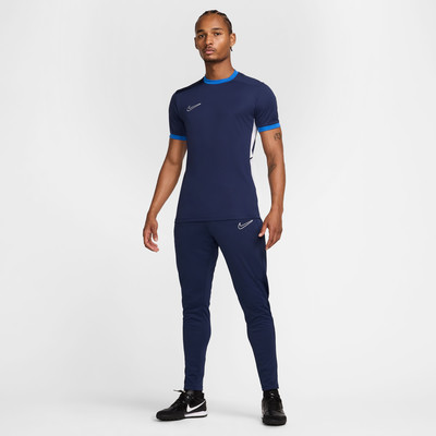 Ein Mann in einem dunkelblauen Nike-T-Shirt und Trainingshose steht vor weißem Hintergrund. Ein Mann in einem dunkelblauen Nike-T-Shirt und Trainingshose steht vor weißem Hintergrund.