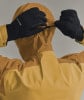 Eine Person mit Handschuhen zieht die Kapuze einer Jacke mit einer Kordel zu.