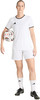 Fußballerin in weißem Trikot und Shorts hält Ball.