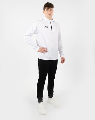 Ein junger Mann in einem weißen Pullover mit kurzem Reißverschluss und schwarzer Hose. Ein junger Mann in einem weißen Pullover mit kurzem Reißverschluss und schwarzer Hose.