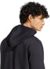 Mann mit lockigem Haar im schwarzen Kapuzenpullover von der Seite.