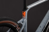 Rahmendetail eines Fahrrads mit orange-grauem Muster und schwarzem Reifen.